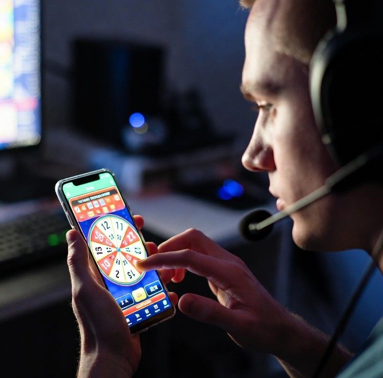 gamer holding a smartphone showing a colorful lottery interface - How Online Lottery Platforms Are Gamifying Number Betting for Gamers